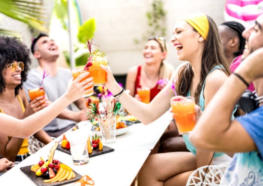 Amis attablés qui trinquent avec des cocktails colorés